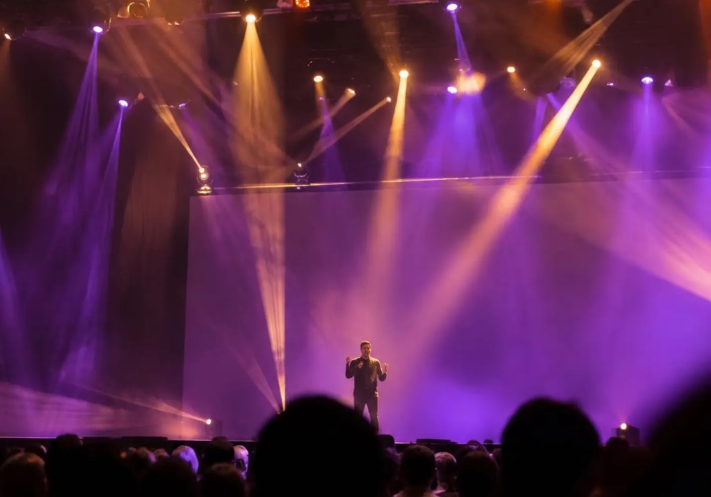 Stage under colored lights with audience silhouettes