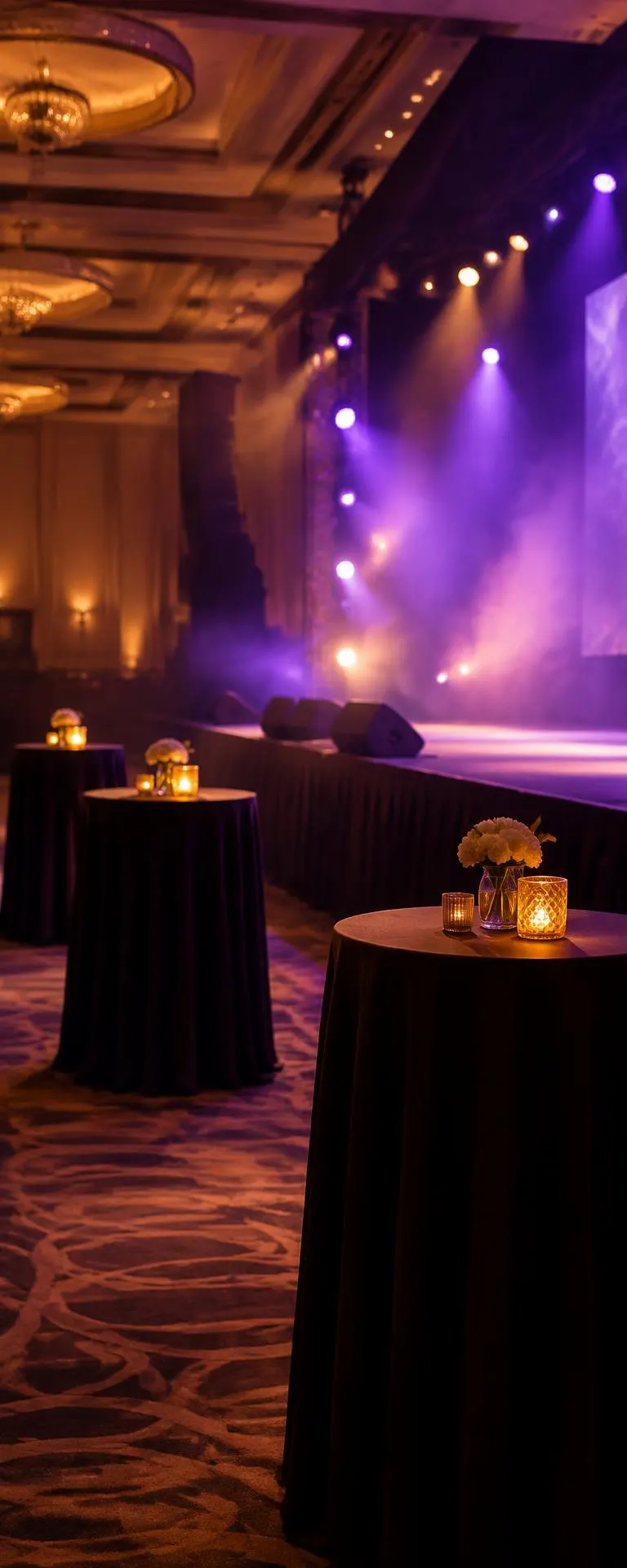 High-top cocktail tables with candles beside the stage edge